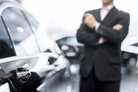 Choosing a car at dealership. Thoughtful grey hair man in formalwear leaning at the car and looking away