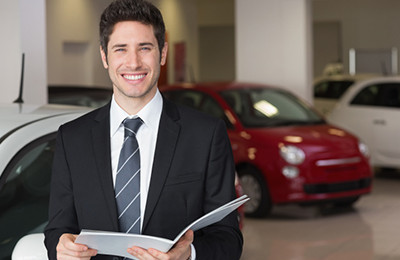 male car buying consultant holding paper work for customers new car